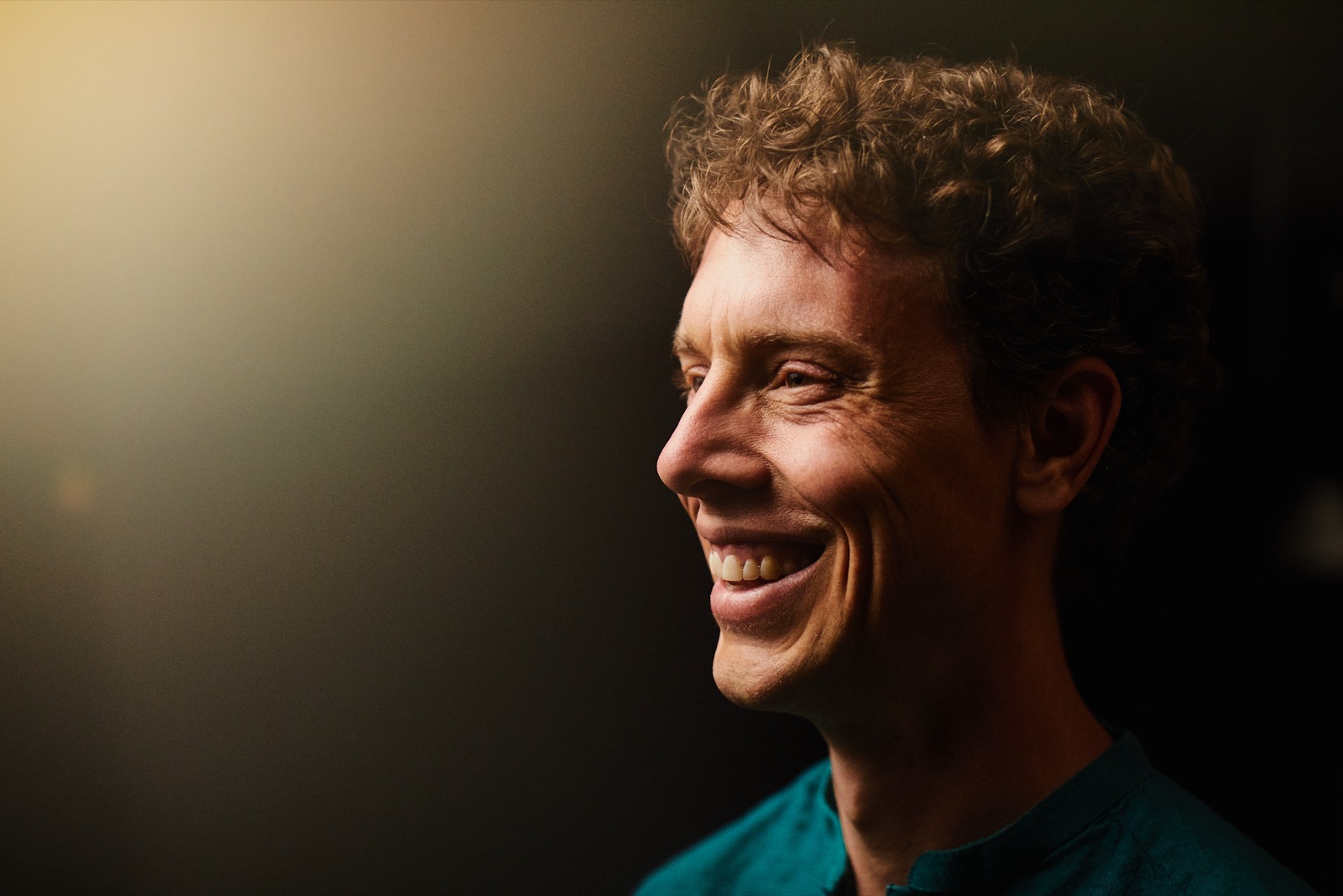 Mark Andreas laughing, lit against a dark background.
