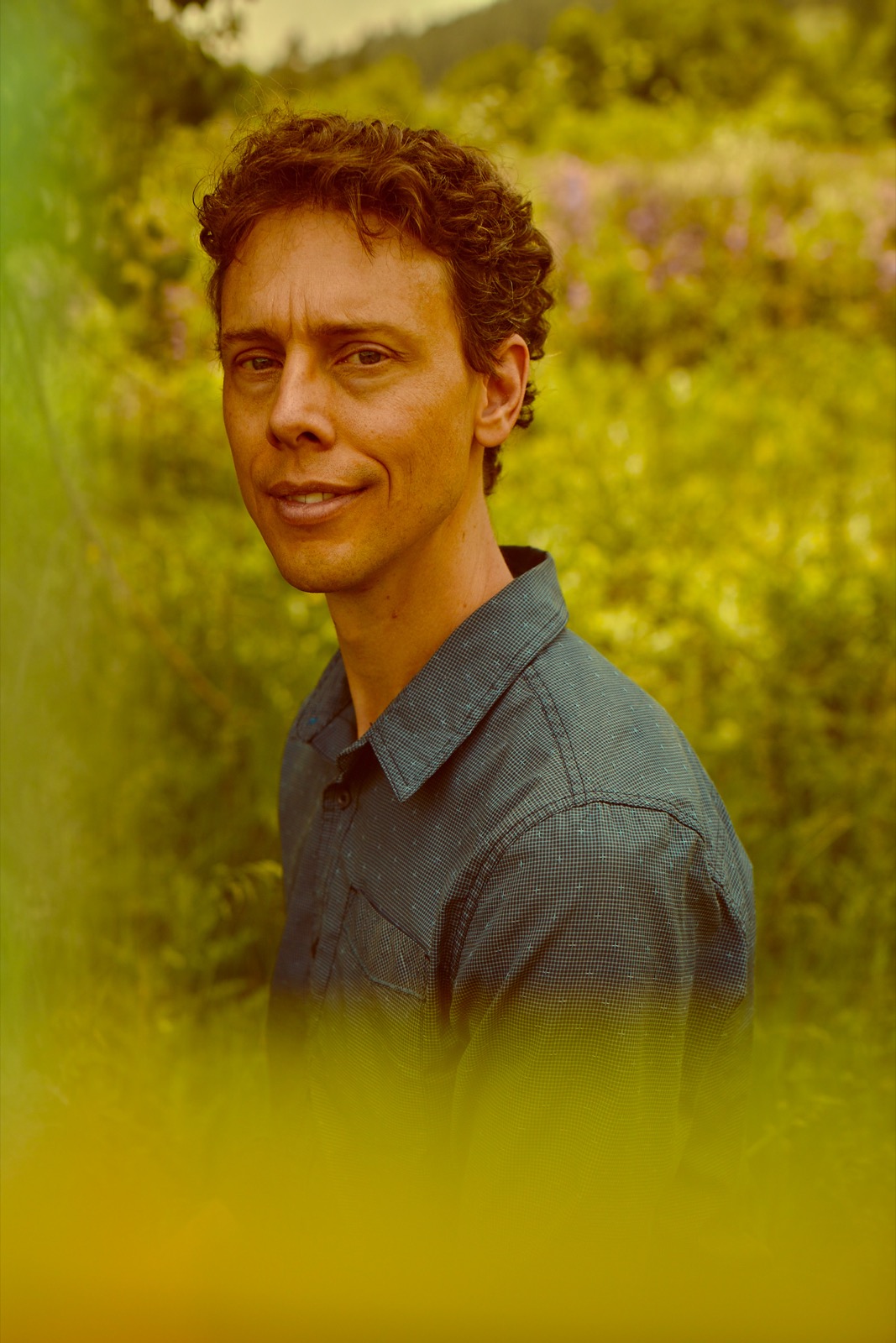 Mark Andreas outdoors in summer greenery, looking to camera.